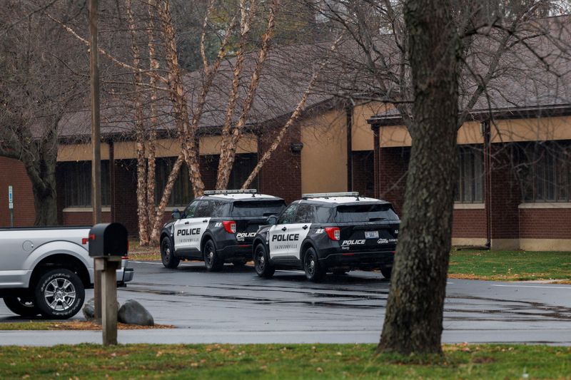 Two police cars are parked outside a brick building.